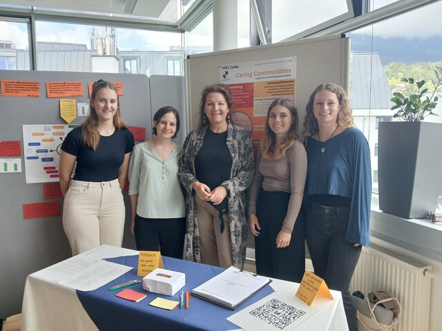 Fünf Frauen stehen vor Pinnwänden zu einem Gruppenfoto zusammen.
