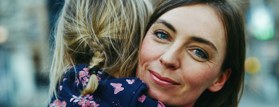 Portrait einer Mutter mit einem Kind auf dem Arm.